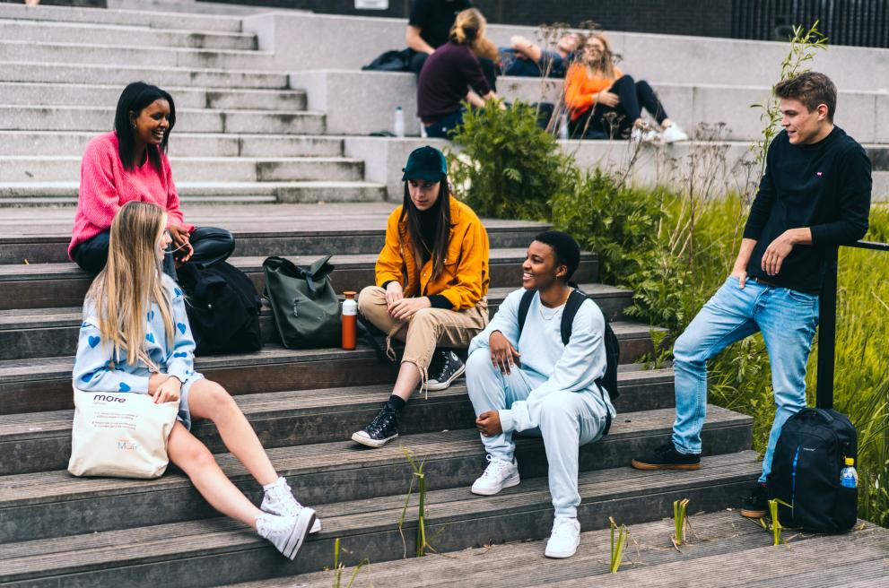 Groep studenten zitten buiten op trappen voor school 