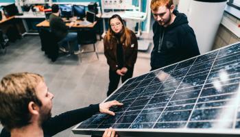 Studenten Energietechnologie en docent bespreken de werking van een zonnepaneel