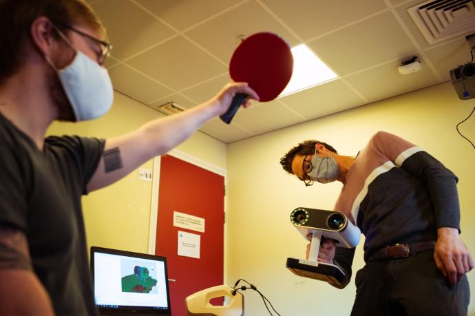 2 personen; één houdt een ping pong palletje, andere een speciale camera